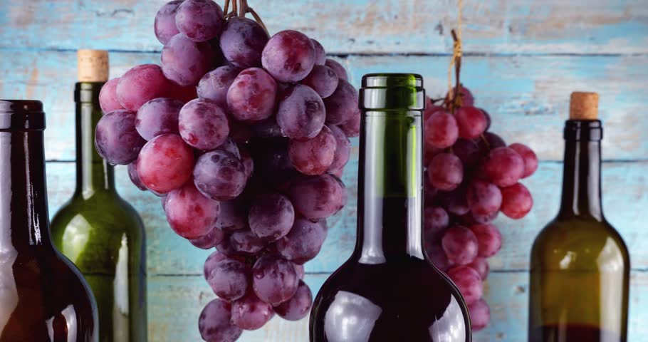Pink grapes and wine bottles on a blue vintage wooden background.