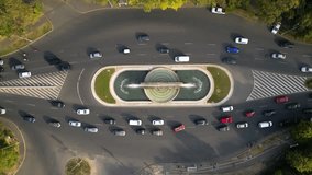 Aerial high angle drone shot of lush green boulevards in autumn. Flyover top down footage of cars in traffic at a fountain inersection in Bucharest Romania. 4k video of green sunny boulevard.