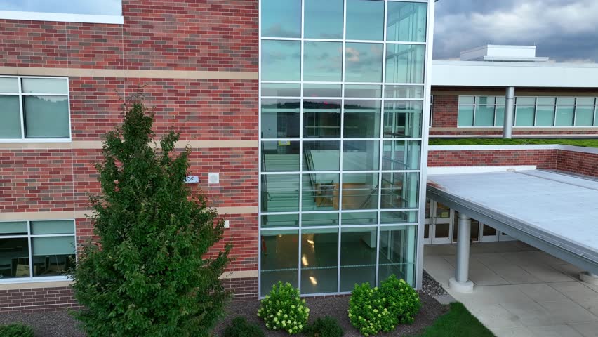 Modern brick school building in USA. Aerial push in on glass stairwell and entrance featuring a green roof.