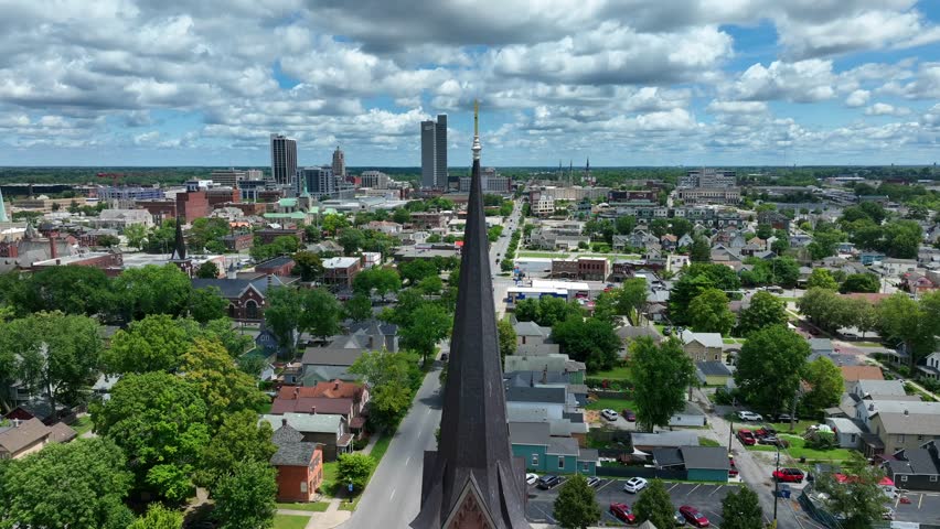 Church steeple with view of Fort Wayne, Indiana skyline. Aerial orbit on summer day.