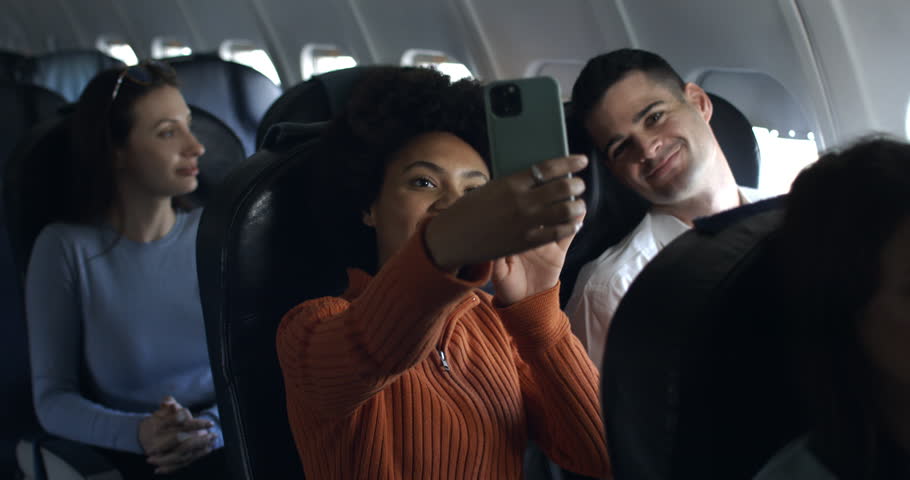 Young woman with afro hair and friends in airplane have a nice moment together and having fun taking pictures and video call and laughing in friendship during the flight from the distant airport. Royalty-Free Stock Footage #1110985389