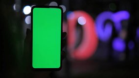 Mobile phone in hand. Women Holding smartphone with red blue neon lighting on dark background. Green chromakey screen. 4K - Powered by Shutterstock - Get 15% off with code: PIKWIZARD15