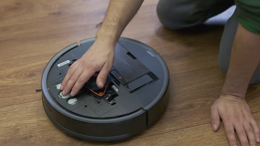 A man is fixing robot vacuum cleaner by hand holding screwdriver to open the cover. Consumables for a robot vacuum cleaner. High quality photo