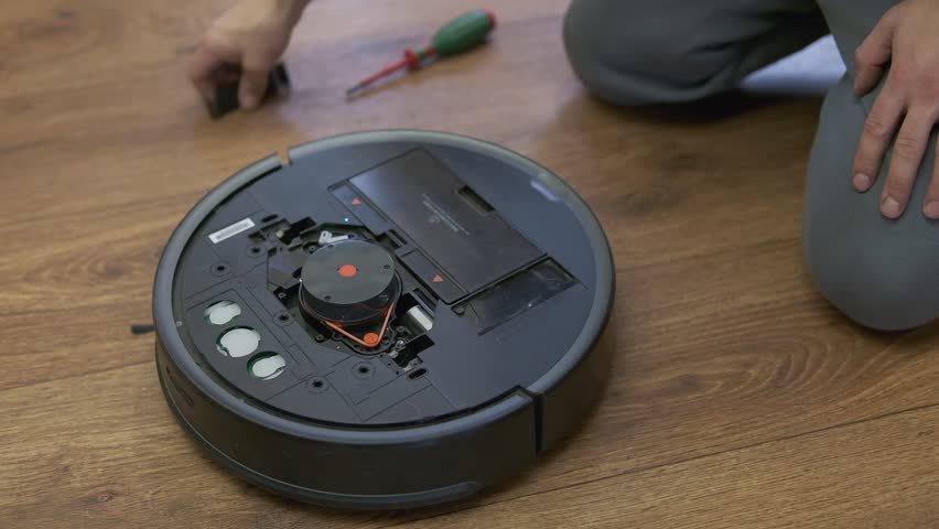 A man is fixing robot vacuum cleaner by hand holding screwdriver to open the cover. Consumables for a robot vacuum cleaner. High quality photo