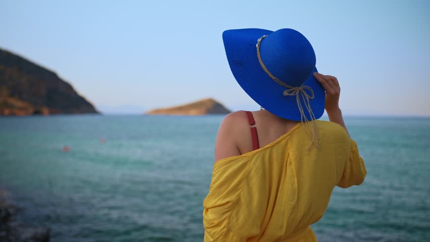 Woman in blue hat against the ocean.