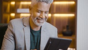 Successful Businessman in Hotel: Mature Man with Digital Tablet Celebrating Big Win. Modern Business, Communication, and Hotel Interior Concept. - Powered by Shutterstock - Get 15% off with code: PIKWIZARD15