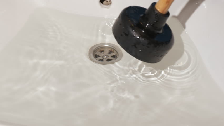 Eliminate the blockage with plunger. A housewife hands try to eliminate the block with a plunger in the kitchen. Royalty-Free Stock Footage #1110998071