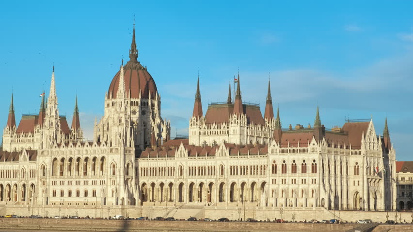 Budapest parliament over blue sunny sky. A view of Danube river bank against sunny facade of Budapest parliament. A concept of holiday in Budapest.