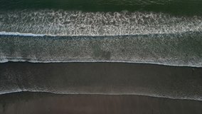 Aerial view of big ocean wave layers in Bali. Wavy beach with black sand during sunset or sunrise - Wide high angle, looking down 90 degree. 4k Cinematic video footage scene for opening or ending.