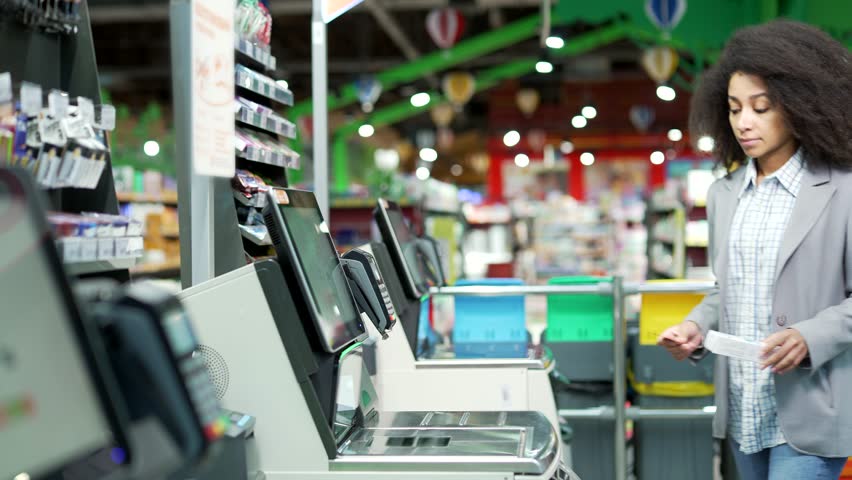 Female shopper using a self-service cashier checkout in a supermarket. Customer scanning produce items using at grocery store self serve cash register. cashier terminal woman pay for products online Royalty-Free Stock Footage #1111015767