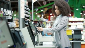 Female shopper using a self-service cashier checkout in a supermarket. Customer scanning produce items using at grocery store self serve cash register. cashier terminal woman pay for products online - Powered by Shutterstock - Get 15% off with code: PIKWIZARD15