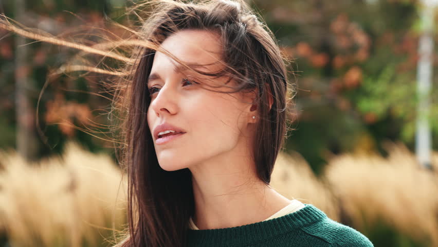 Portrait of beautiful caucasian woman outdoors. Beautiful young model in warm sweater. Fashion stylish pretty female posing in the street in city. Cheerful and happy. Closeup. Wind blows hair Royalty-Free Stock Footage #1111018263