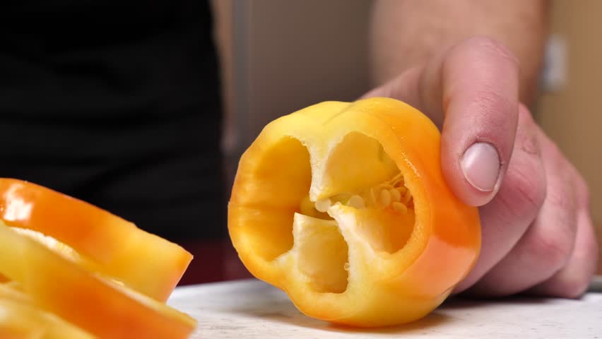 male hand cuts yellow pepper close-up, slicing pepper into circles