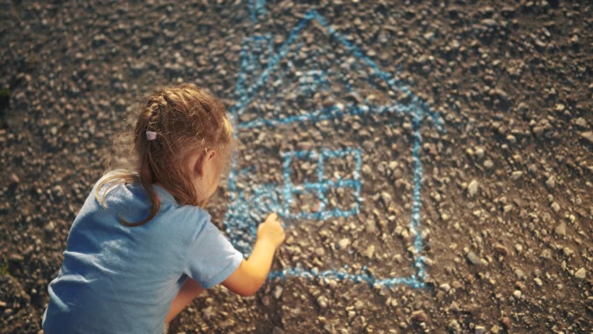 girl draws home on the asphalt. happy family kid concept. a little girl sits on the asphalt during the day and draws house with blue chalk. girl draws with blue dream chalk on the dark asphalt Royalty-Free Stock Footage #1111021923