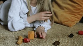 Wooden blocks. 
A girl plays with wooden balancing cubes. Educational games for children. Wooden blocks in shapes of gems of various colours. 
Horizontal video.