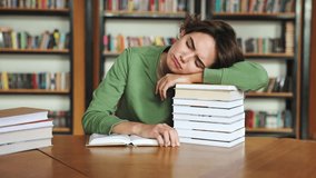 Young sad sleepy college student girl wearing green casual clothes read book do research rub eyes sit at desk studying visit university library for learning new information indoor. Knowledge concept - Powered by Shutterstock - Get 15% off with code: PIKWIZARD15