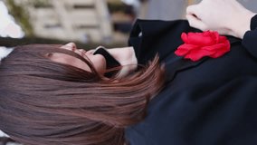 business lady talking on the phone on the street in the city. vertical video. a girl in a black jacket with a red flower on her chest makes a phone call.
