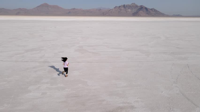 Aerial shot of an Asian woman jogging across the Bonneville Salt Flats flats in Utah