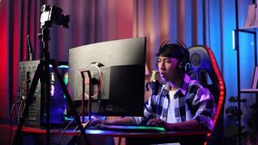 Asian Boy Streamer Stretching While Playing Game Over Network On Personal Computer. Live Stream Video Game, Desk Illuminated By Rgb Led Strip Light