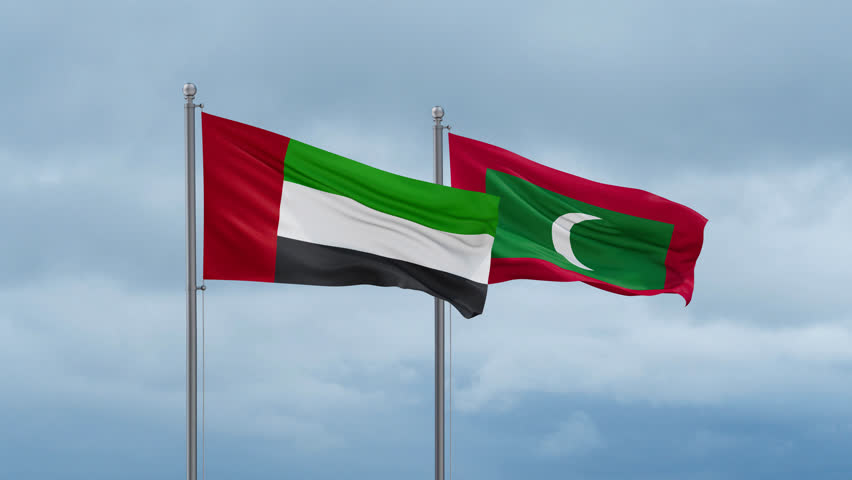 Maldives flag and United Arab Emirates UAE flag waving together on cloudy sky, endless seamless loop, two country relations concept