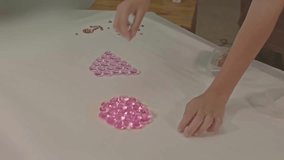 .The boy carefully uses the diamonds to make letters in the studio..high quality video 4K. studio shot..Playing with colorful gems is a great way for children to learn. ..colorful gems background