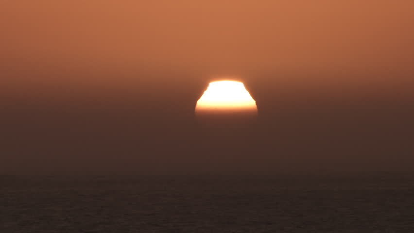 Sunrise time lapse over large body of water with sun rising through thick haze becoming a bright and hot day. | Shutterstock HD Video #1111037245