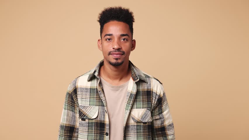 Young fun man of African American ethnicity he wear shirt casual clothes look camera surprised ask what wow omg no way say yes celebrating put hands on face isolated on plain beige brown background | Shutterstock HD Video #1111038451