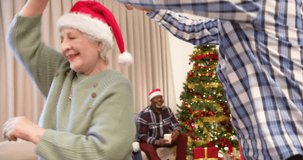 Animation of merry christmas text over diverse senior friends dancing at christmas at home. Chirstmas, celebration and tradition concept digitally generated video.