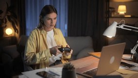 Beautiful young woman with joystick controller playing video games on laptop at late night alone Upset female lose the competition at home Defeat Game addiction concept
