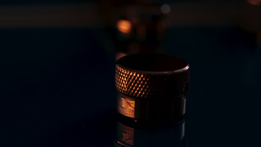 Extreme close up of a guitar volume or tone knob or potentiometer. Camera rotating around the piece to orbit. Reflections move on knurling of the control knob and the blue guitar surface. Royalty-Free Stock Footage #1111050613