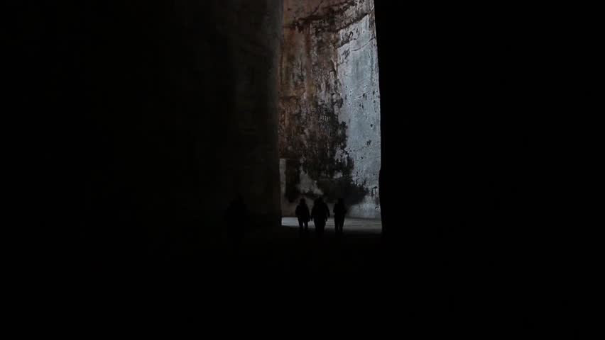 syracuse sicily italy ear of dionysius close up exit entrance shot from inside with people exiting silhouettes contrast dark and light