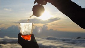 Slow-motion video tea ceremony in mountains above clouds. Person pours hot tea from teapot into glass under bright morning sun. Captivating display tea ceremony outdoor for all tea ceremony enthusiast - Powered by Shutterstock - Get 15% off with code: PIKWIZARD15