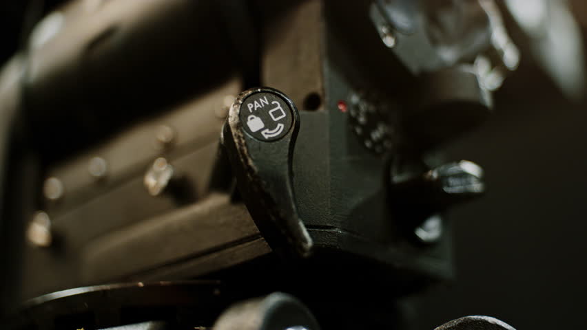 The pan lock of a professional high-end cinema tripod fluid head being adjusted, first locking then opening.