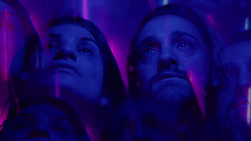 Young man and woman standing in dark studio with blue and purple light and staring up with hope. Kaleidoscope effect, multiple exposure