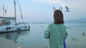 The girl feeding seagulls near the sea. 4k footage UHD 3840x2160 