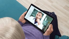 Online medicine with remote medical assistance for elderly woman patient holding tablet computer having consultation online with doctor.