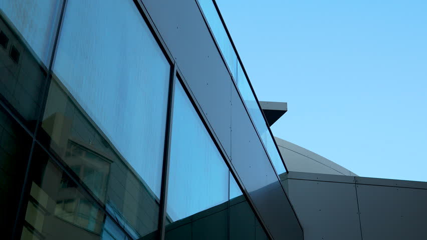 Modern architectural detail with angled glass facade against sky. Royalty-Free Stock Footage #1111067329