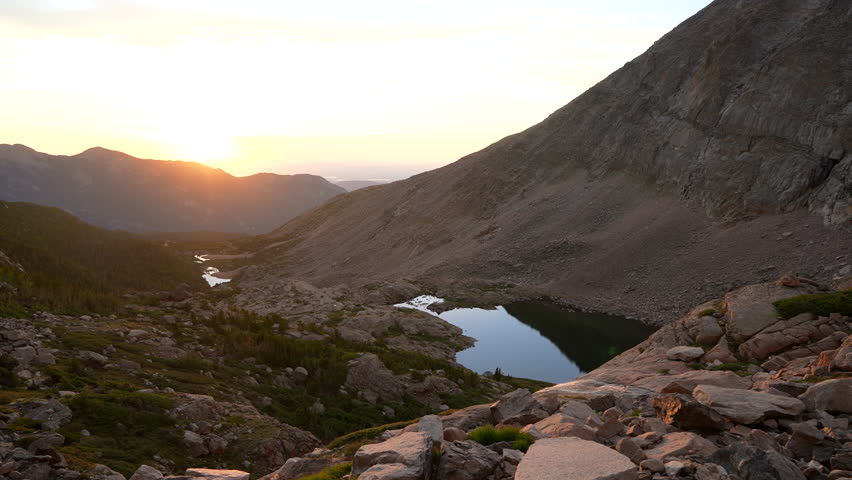 Cinematic first light Longs Peak 14er sunrise Rocky Mountain National Park above treeline Colorado towards Denver Boulder Estes Park Erie sunny late summer green dramatic landscape pan slowly left