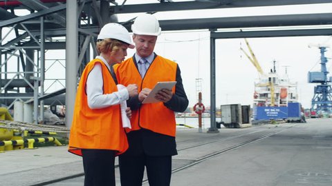 Business People in Safety Vests Using Tablet in Industrial Environment. Shot on RED Cinema Camera in 4K (UHD).
