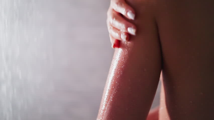 Woman peels skin with scrub in shower cabin closeup. Elegant lady cleans body skin with natural cosmetic product in bathroom. Enjoying skincare spa