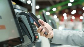 Close up Woman At Counter Buy electronic payment supermarket smartphone close-up Female hand with a mobile phone in hands pay paid for purchases in stores Contactless NFC Terminal Closeup card reader - Powered by Shutterstock - Get 15% off with code: PIKWIZARD15