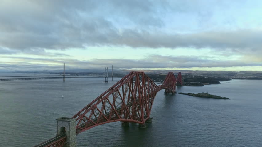 Cinematic tilt down aerial drone shot of Forth Rail Bridge, Scotland, Forth Road bridges in background, clear winter day.  Royalty-Free Stock Footage #1111081529