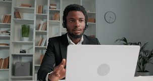 African businessman having online meeting with his subordinates, using laptop. Man speaking about new startup project , using headphones. Video call with partners and colleagues.