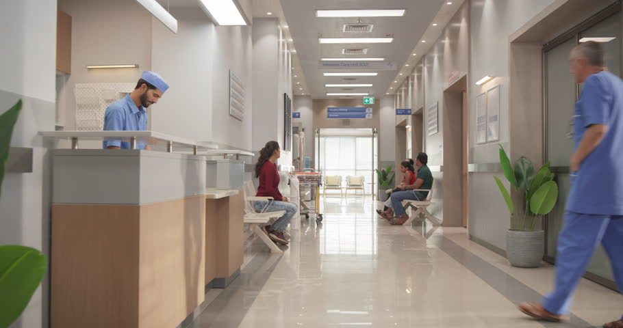 Tracking Dolly Shot of Hospital Corridor and Lobby Filled with Group of Diverse Indian Patients Waiting for their Appointments. Modern Health Clinic with Active Doctors, Nurses and Staff Working Royalty-Free Stock Footage #1111088999