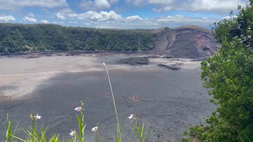 Cinematic wide panning shot of the hiking trail in the Kilauea Iki dry lava lake bed from an overlook in Hawai