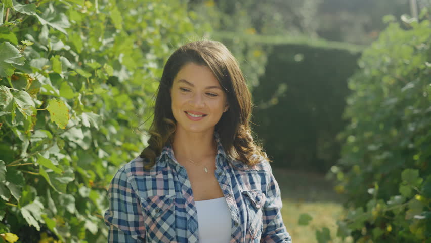 Young smiling woman touching vine and checking grapes in the vineyard while walking | Shutterstock HD Video #1111093085