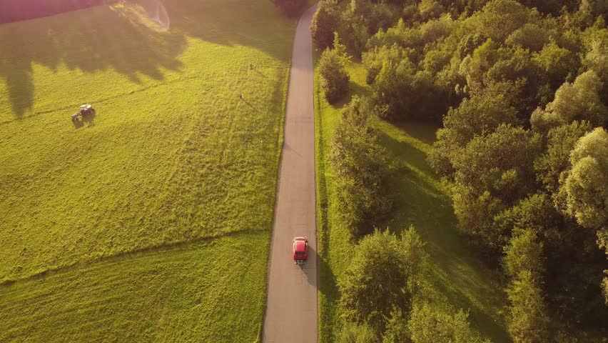 4k drone shot of a red car driving in a hilly Landscape.