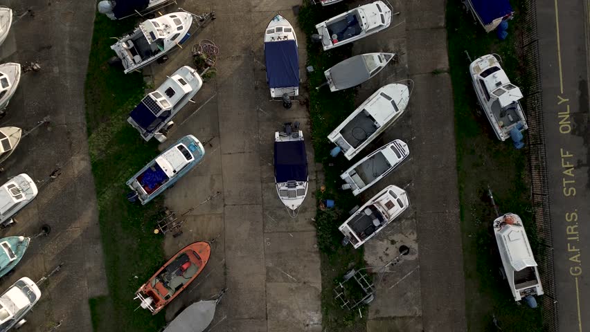 An aerial over many of parked boats next to a parking lot with cars