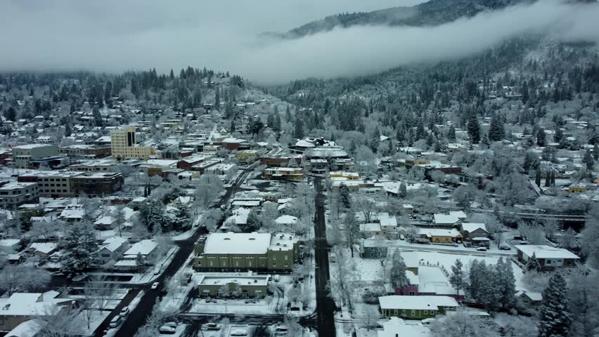 Ashland, Oregon, USA, Winter 2023. Downtown. On a rare snow day moving West to East along Main Street. The downtown area has Ashland Springs Hotel on the left, and back to the right is Lithia Park.