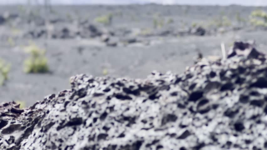 Cinematic booming up shot from foreground lava rock to reveal volcanic landscape at the crater